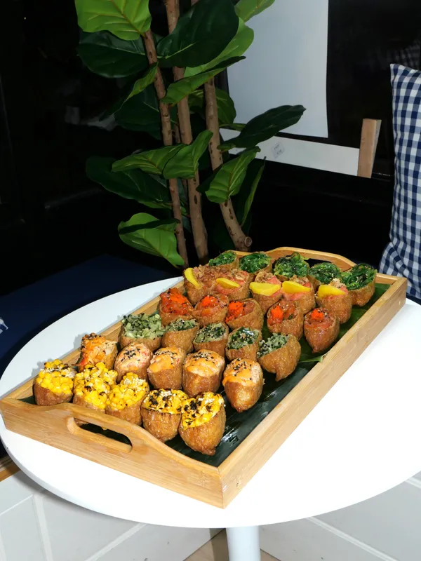 Wooden tray of colorful topped inari sushi pockets